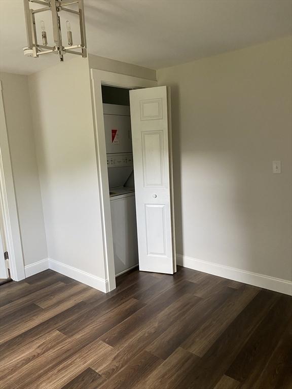 7 Washington St, Groveland, MA 01834 - empty room featuring estacked washer and dryer, a chandelier, and dark wood-style flooring