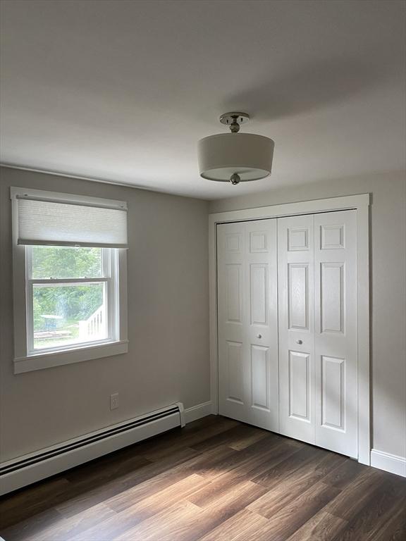 7 Washington St, Groveland, MA 01834 - unfurnished bedroom with baseboard heating, dark wood-type flooring, and a closet