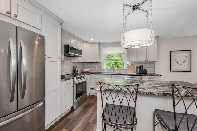 7 Washington St, Groveland, MA 01834 - kitchen with stainless steel appliances, a breakfast bar, dark wood-style floors, tasteful backsplash, and decorative light fixtures
