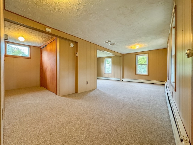 bonus room featuring wood walls, light colored carpet, and a baseboard radiator