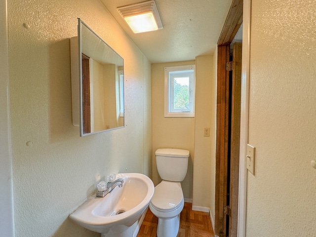 bathroom featuring sink, a textured ceiling, parquet floors, and toilet