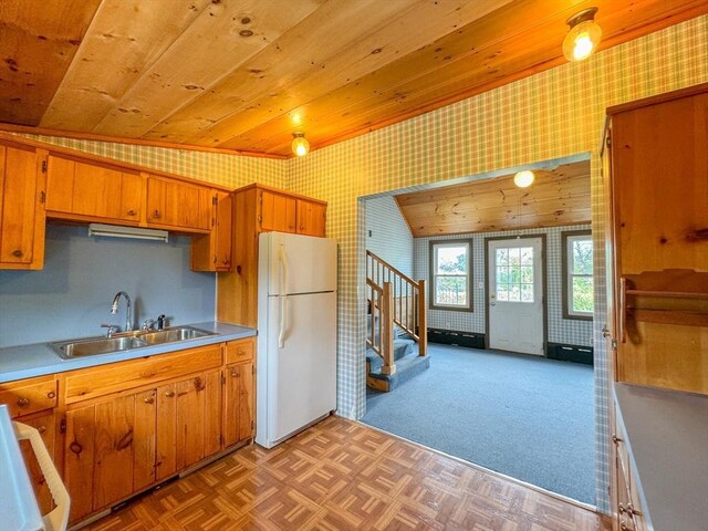 kitchen featuring wood ceiling, vaulted ceiling, white fridge, sink, and light carpet