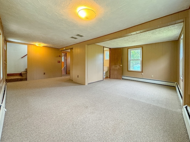 spare room with a baseboard radiator, wooden walls, a textured ceiling, and carpet flooring