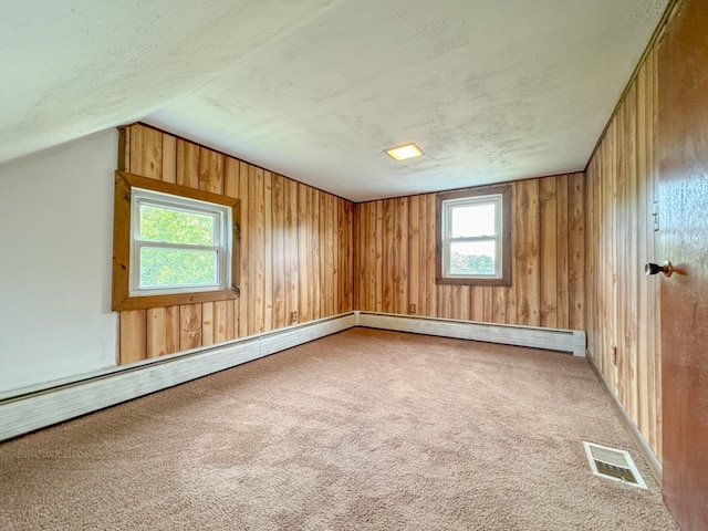 bonus room featuring vaulted ceiling, a textured ceiling, wood walls, and carpet flooring