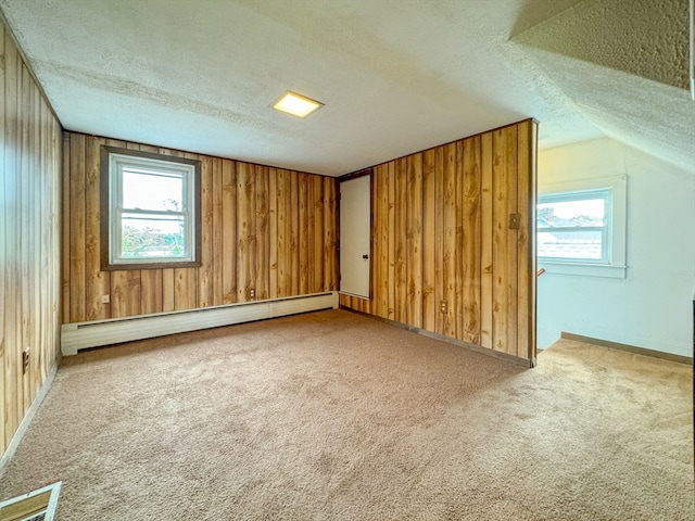 bonus room with a baseboard radiator, wood walls, and a textured ceiling