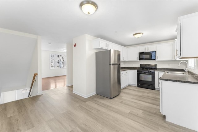 14 Watson St Unit 14, Lowell, MA 01852 - kitchen featuring black appliances, dark countertops, light wood finished floors, and white cabinetry