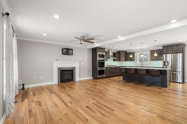 living room with sink, ornamental molding, ceiling fan, and light wood-type flooring