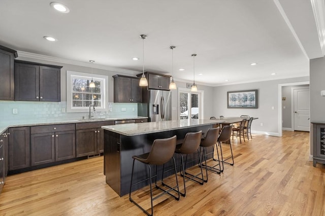 kitchen featuring sink, a center island, pendant lighting, and stainless steel fridge