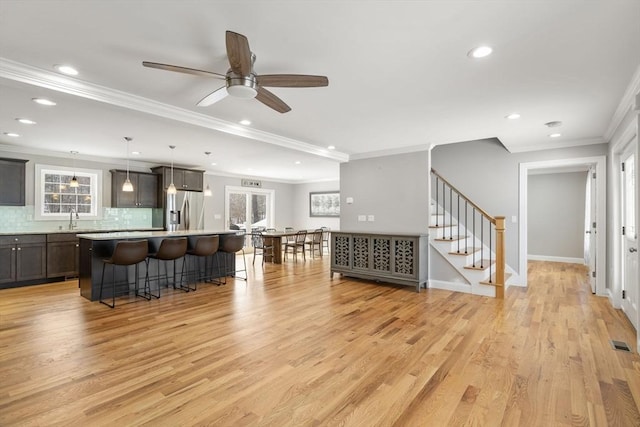 living room with crown molding, sink, ceiling fan, and light hardwood / wood-style flooring