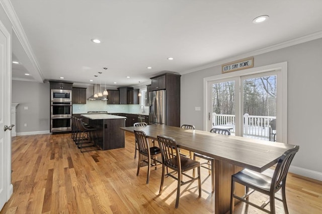 dining room with sink, light hardwood / wood-style flooring, and ornamental molding