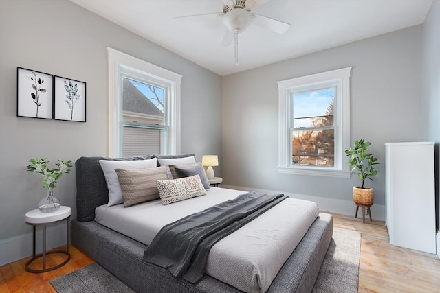 bedroom with ceiling fan, multiple windows, and light hardwood / wood-style flooring