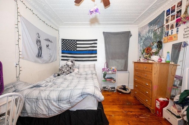bedroom with hardwood / wood-style flooring, ornamental molding, an ornate ceiling, and a ceiling fan