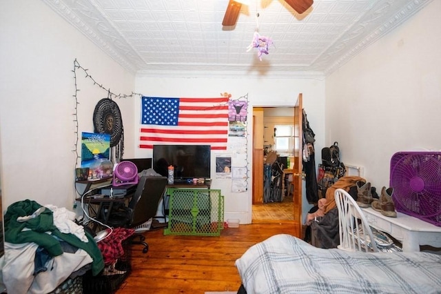 bedroom with an ornate ceiling, wood-type flooring, ornamental molding, and ceiling fan