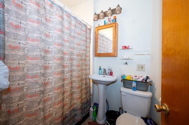 bathroom with toilet, curtained shower, and a sink