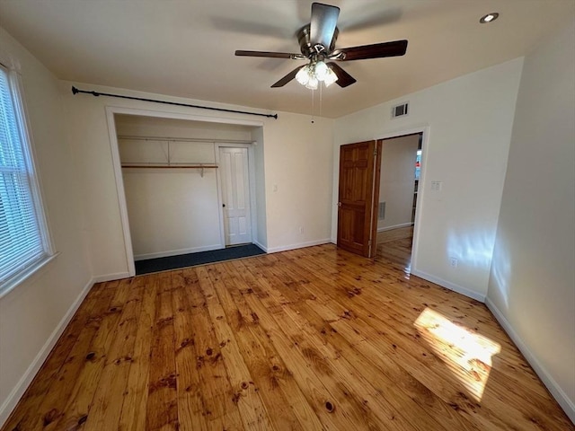 unfurnished bedroom featuring light wood-type flooring, a closet, baseboards, and ceiling fan