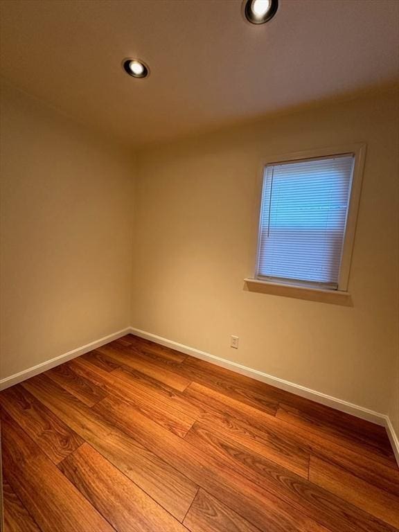spare room with baseboards, wood finished floors, and recessed lighting