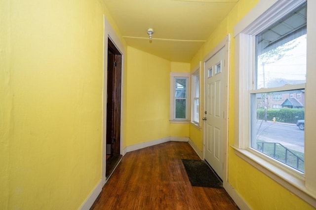 corridor with dark wood-style flooring and baseboards