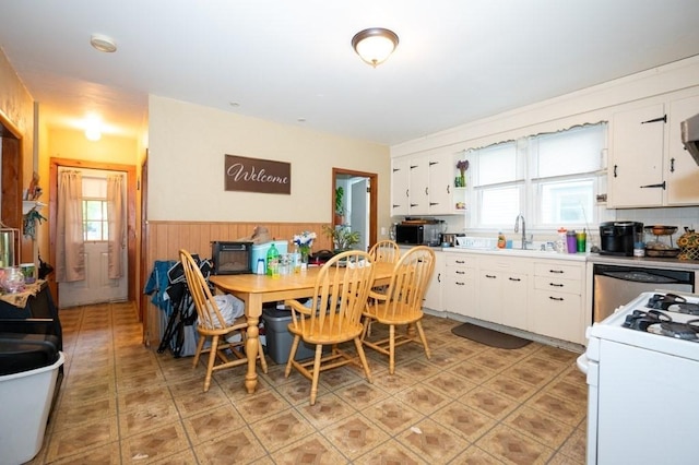 dining space with wainscoting, plenty of natural light, wooden walls, and light tile patterned flooring