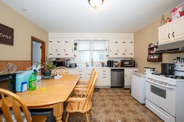 kitchen featuring dishwasher, white gas range oven, under cabinet range hood, white cabinetry, and a wainscoted wall