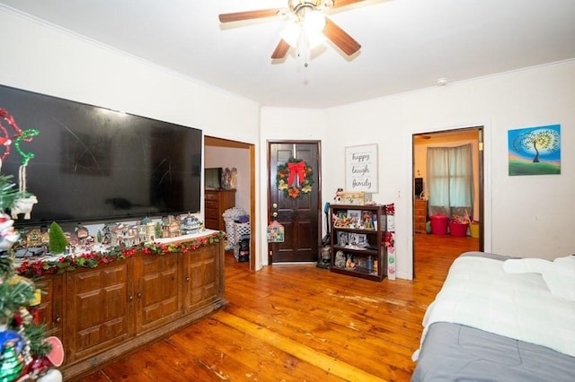 bedroom featuring light wood finished floors, crown molding, and a ceiling fan
