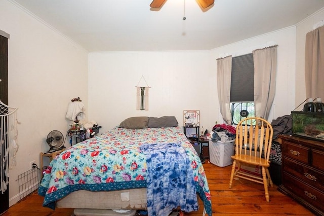 bedroom featuring wood-type flooring, ornamental molding, and ceiling fan