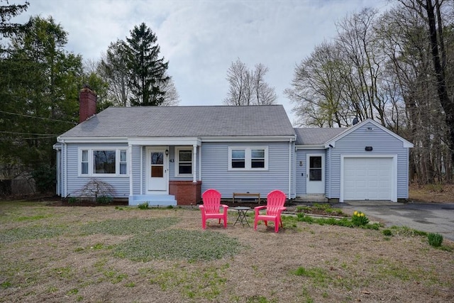 view of front of home with roof with shingles, driveway, a chimney, an attached garage, and a front yard
