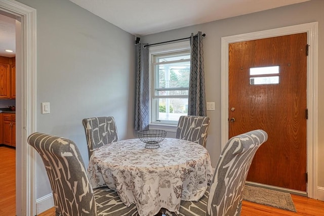 dining space with light wood finished floors and baseboards
