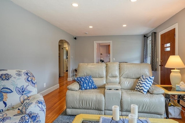 living room featuring baseboards, wood finished floors, arched walkways, and recessed lighting