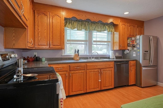 kitchen featuring brown cabinetry, stainless steel appliances, light wood-type flooring, and a sink