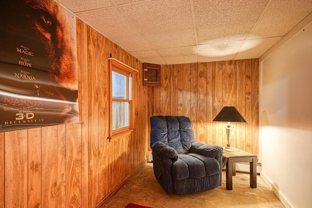 living area with wooden walls, carpet flooring, and baseboards