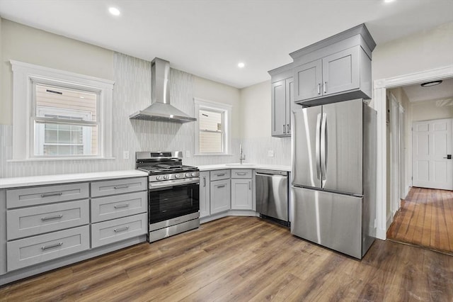 18 Lyon St Unit 2, Boston, MA 02122 - kitchen featuring wall chimney range hood, appliances with stainless steel finishes, gray cabinetry, a sink, and dark wood-style floors