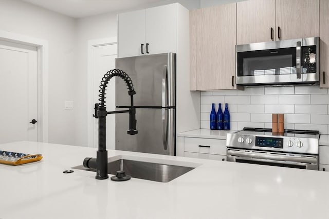10 Somerset Unit 403, Winthrop, MA 02152 - kitchen featuring appliances with stainless steel finishes, light countertops, backsplash, and a sink