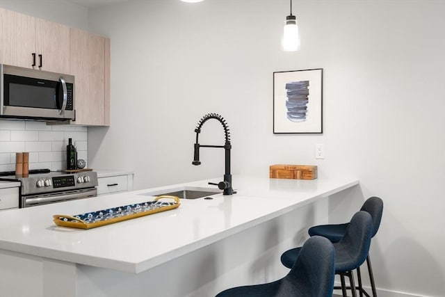 10 Somerset Unit 403, Winthrop, MA 02152 - kitchen featuring stainless steel appliances, a kitchen bar, a sink, decorative backsplash, and a peninsula