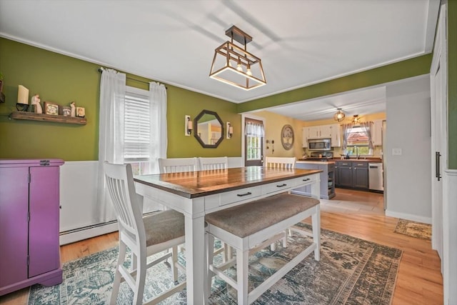 217 Hathaway Commons Rd, Fall River, MA 02720 - dining space featuring baseboard heating, light wood finished floors, and crown molding