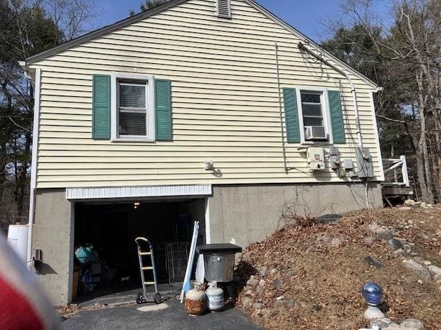 view of side of property featuring aphalt driveway, cooling unit, and an attached garage