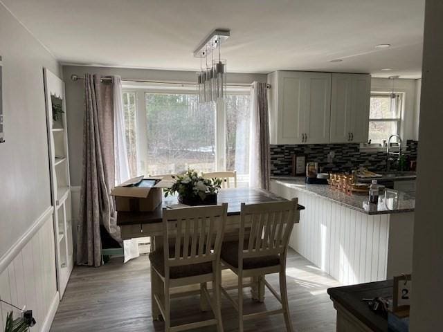 dining area with wood finished floors and a wainscoted wall