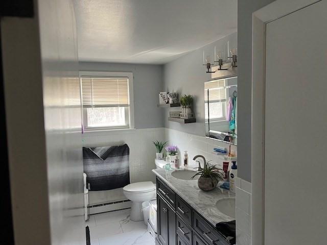 bathroom featuring a wealth of natural light, marble finish floor, toilet, and a baseboard heating unit