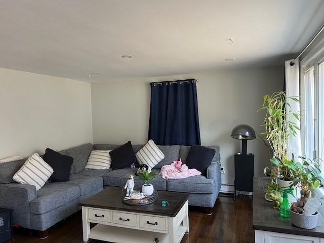 living area with dark wood-style flooring and a baseboard radiator