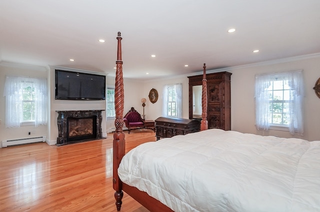 bedroom featuring crown molding, light hardwood / wood-style flooring, a premium fireplace, and a baseboard radiator