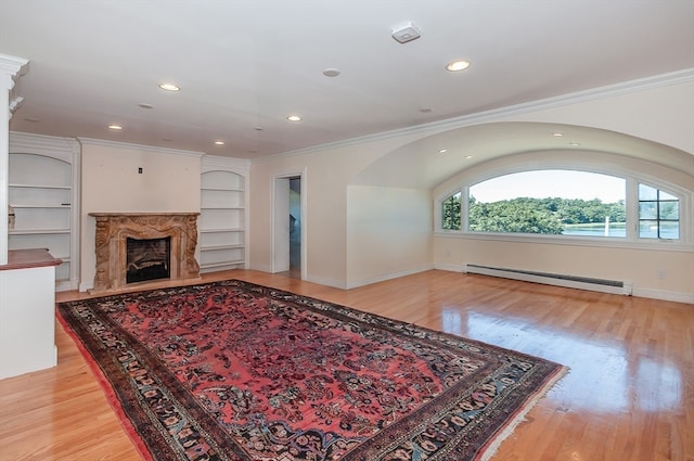 living room featuring built in shelves, a premium fireplace, light hardwood / wood-style flooring, and a baseboard radiator