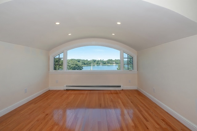 additional living space with lofted ceiling, a healthy amount of sunlight, baseboard heating, and light wood-type flooring