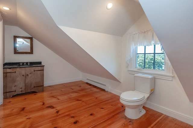 bathroom with vanity, lofted ceiling, wood-type flooring, toilet, and a baseboard heating unit