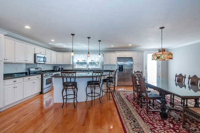 kitchen with white cabinets, pendant lighting, and stainless steel appliances