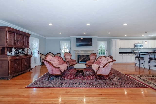 living room with ornamental molding, a high end fireplace, and light wood-type flooring