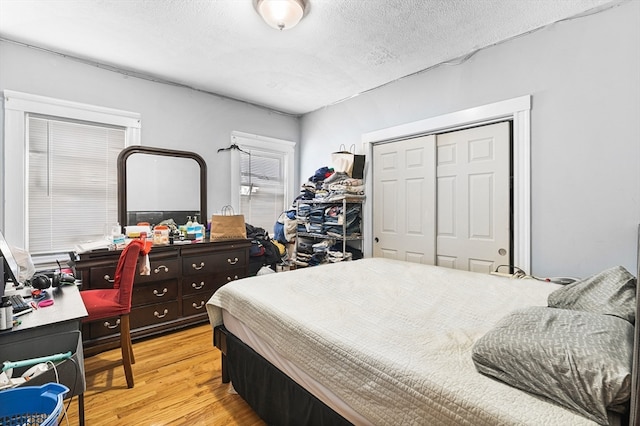 bedroom with a textured ceiling, light hardwood / wood-style flooring, and a closet