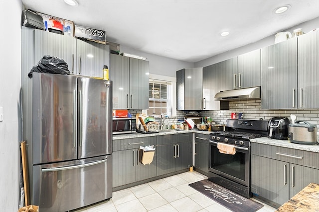 kitchen with gray cabinetry, light stone countertops, and stainless steel appliances