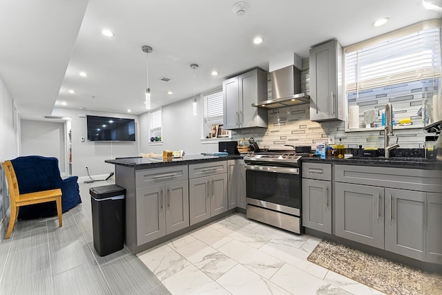 kitchen with pendant lighting, wall chimney exhaust hood, stainless steel range oven, and gray cabinetry