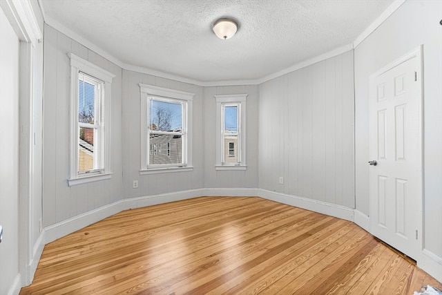 empty room featuring hardwood / wood-style floors, ornamental molding, and a textured ceiling