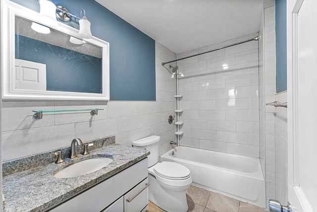 full bathroom featuring tiled shower / bath combo, tile patterned flooring, toilet, vanity, and tile walls