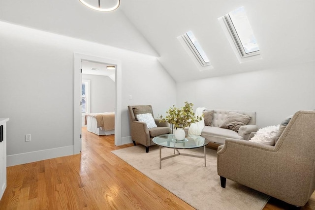 living room with lofted ceiling with skylight, baseboards, and light wood-style floors